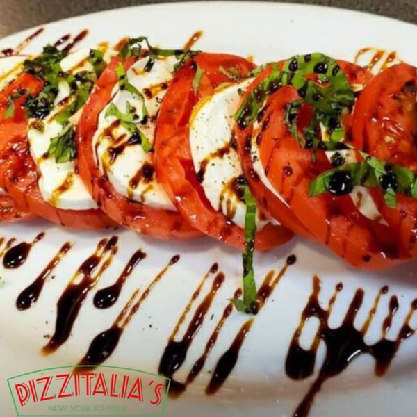 Pizzitalia's Caprese salad with sliced tomatoes, mozzarella, basil, and balsamic glaze.